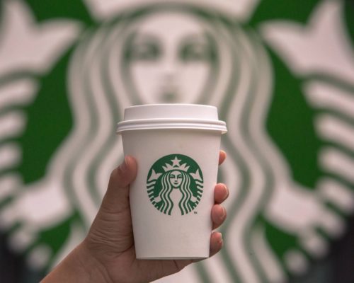 Starbucks logo background with Starbucks cup in hand Blakeney Town Center Charlotte, NC